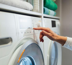Person bruger vaskemaskine korrekt og forlænger levetiden med 6 gode råd